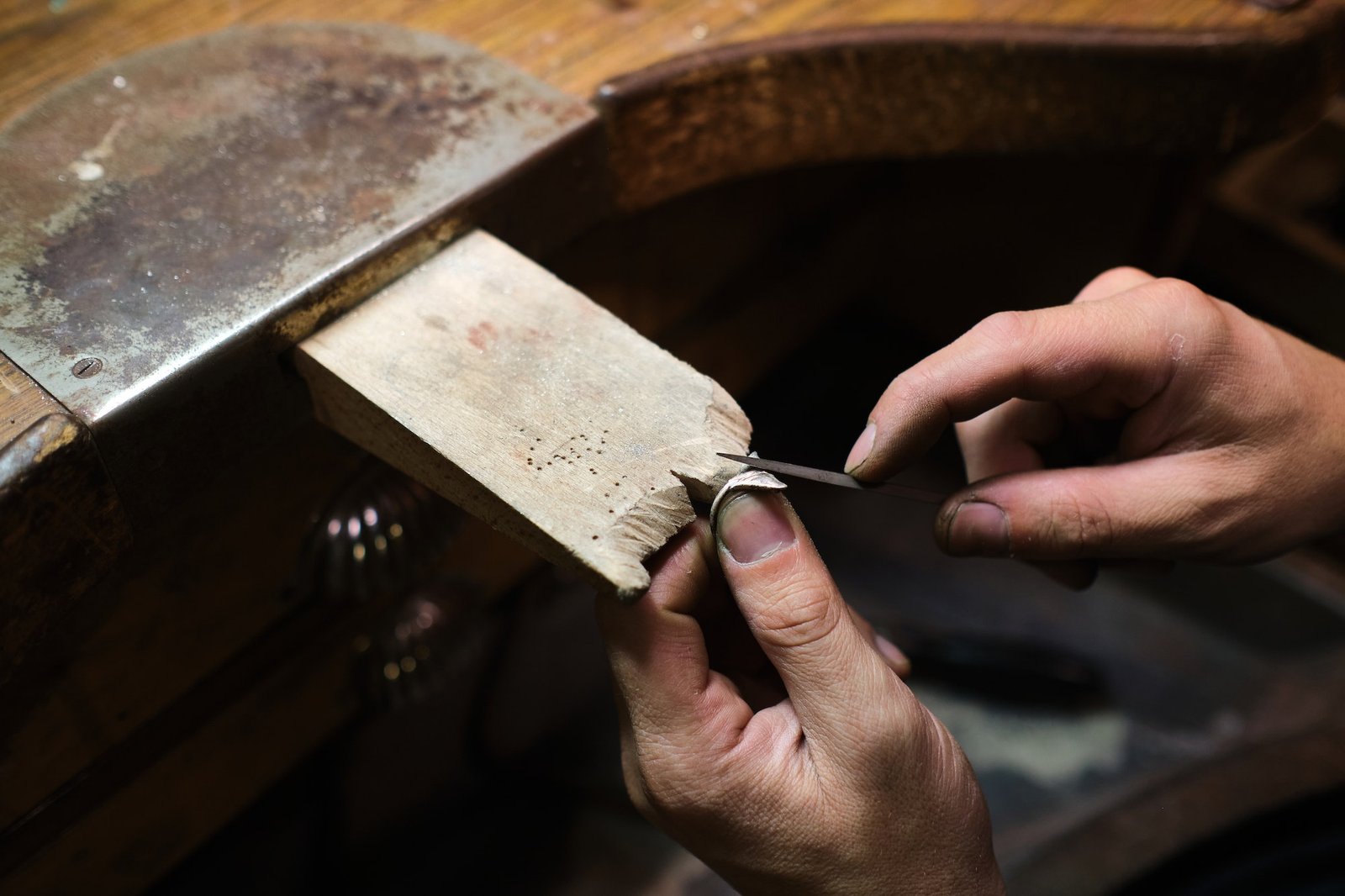 Craftsman shaping jewel with file tool in workshop