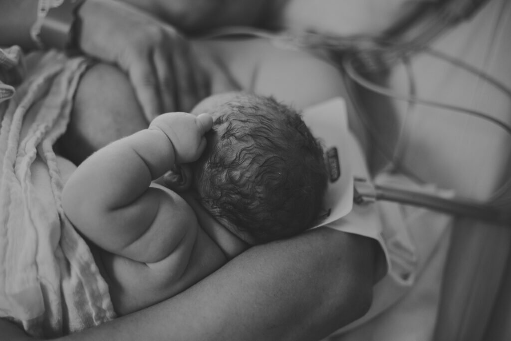 Newborn baby girl breastfeeding after birth