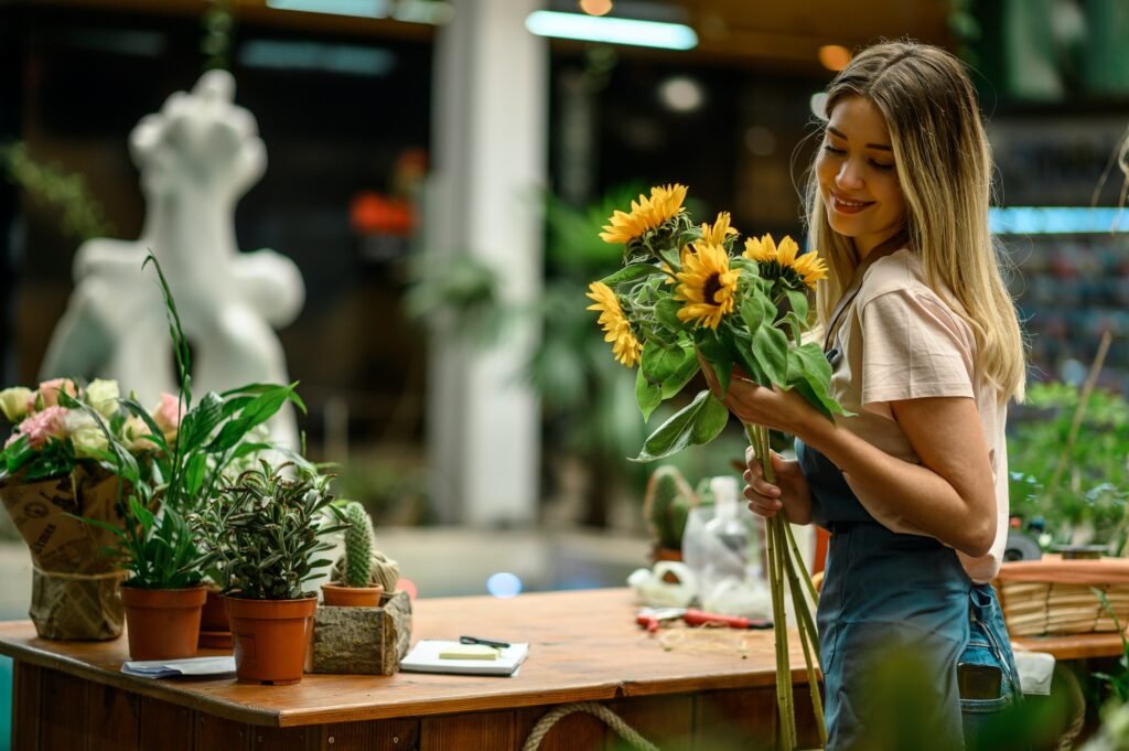 Florist standing and holding bouquet of sunflowers in flower shop