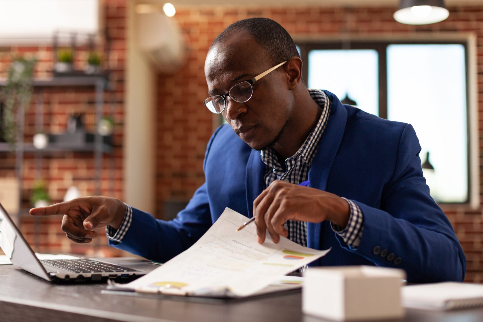 Business man analyzing papers on clipboard to plan marketing strategy with laptop