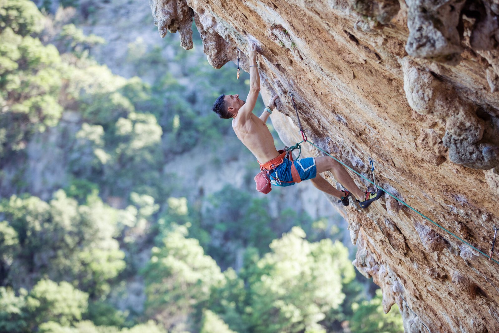 Rock climber on challenging route on overhanging cliff